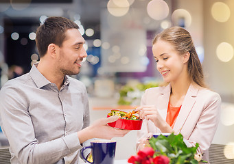 Image showing happy couple with present and flowers in mall