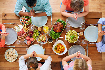 Image showing group of people at table praying before meal