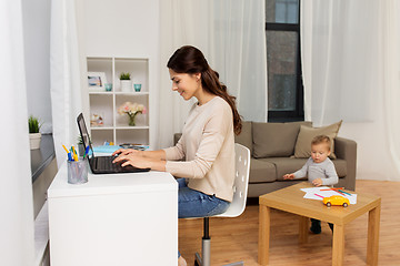 Image showing happy mother with baby and laptop working at home