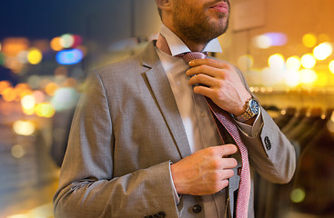 Image showing close up of man tying tie at clothing store