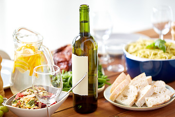 Image showing bottle of wine and food on served wooden table