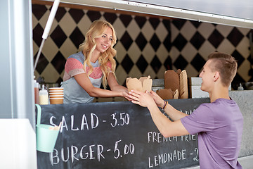 Image showing saleswoman at food truck serving male customer