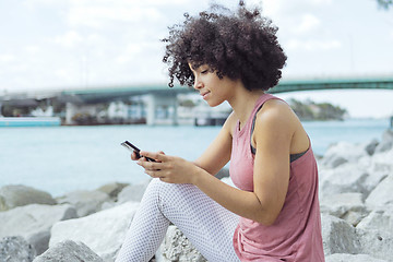 Image showing Casual young woman using phone on embankment