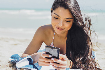 Image showing Pretty girl using phone on beach