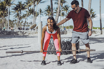 Image showing Man supporting girl with squats on beach