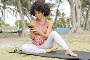 Image showing Chilling black girl using phone on mat