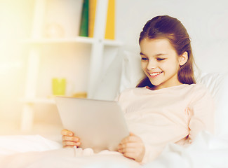 Image showing happy girl with tablet pc lying in bed at home