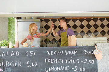 Image showing couple of sellers making high five at food truck