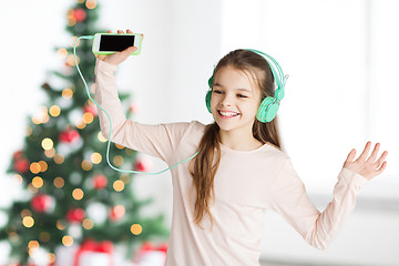 Image showing girl with smartphone and headphones at christmas