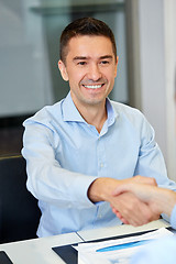 Image showing smiling businessman making handshake at office