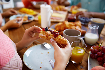 Image showing hands of woman eating croissant for breakfast