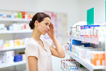 Image showing customer with headache choosing drugs at pharmacy