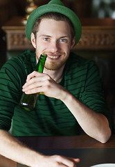 Image showing man drinking beer from green bottle at bar or pub