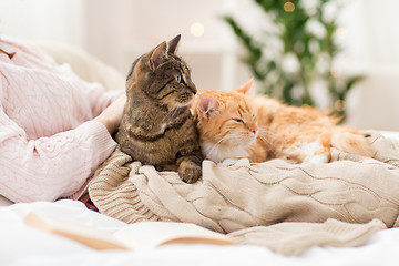 Image showing close up of owner with red and tabby cat in bed