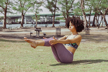 Image showing Girl practicing abdomen muscles on meadow