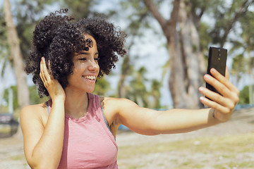 Image showing Laughing young girl taking selfie in park