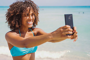 Image showing Cheerful ethnic woman taking selfie on beach