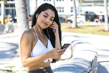 Image showing Confident trendy brunette listening to music outside