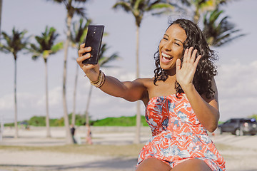 Image showing Pretty black girl speaking online in park