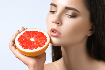 Image showing Pretty woman with delicious grapefruit in her arms.