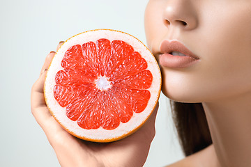 Image showing Pretty woman with delicious grapefruit in her arms.