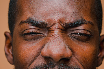 Image showing The squint of Afro American stylish man at brown studio wall