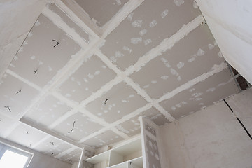 Image showing The ceiling is covered with plasterboard sheets during the repair process