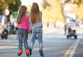 Image showing Two girls girlfriends rollerblading on the mall, rear view