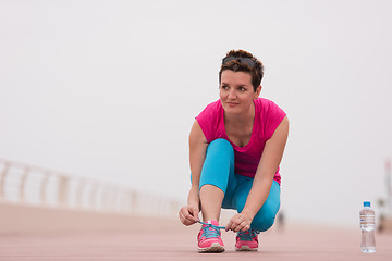 Image showing Young woman tying shoelaces on sneakers