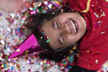 Image showing kid blowing confetti while lying on the floor