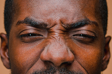 Image showing The squint of Afro American stylish man at brown studio wall