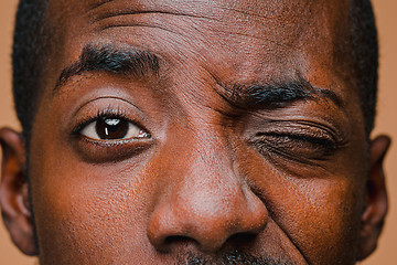 Image showing The squint of Afro American stylish man at brown studio wall