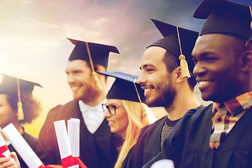 Image showing happy students in mortar boards with diplomas