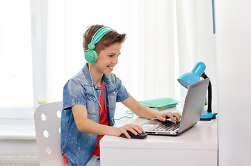 Image showing boy in headphones playing video game on laptop