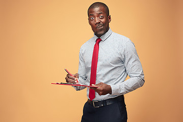 Image showing Attractive standing Afro-American businessman writing notes