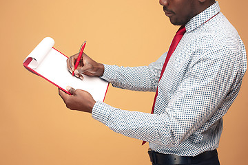 Image showing Attractive standing Afro-American businessman writing notes