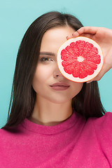 Image showing Pretty woman with delicious grapefruit in her arms.