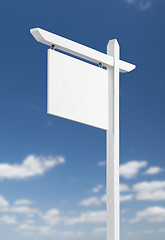 Image showing Blank Real Estate Sign Over A Blue Sky with Clouds.