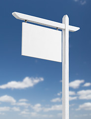 Image showing Blank Real Estate Sign Over A Blue Sky with Clouds.