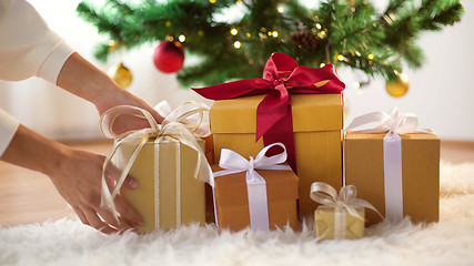 Image showing hands putting gift boxes under christmas tree