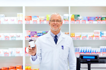 Image showing senior apothecary with drug at pharmacy