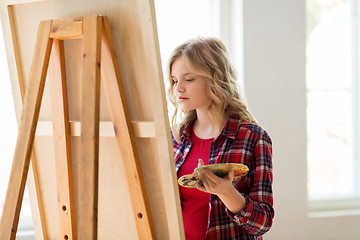 Image showing student girl with easel painting at art school