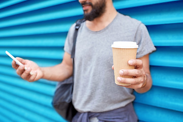 Image showing man with coffee cup and smartphone over wall