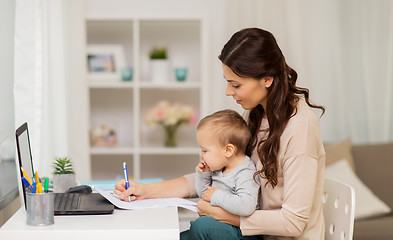 Image showing happy mother with baby and papers working at home