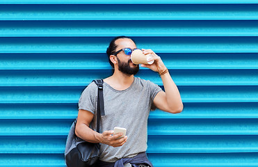 Image showing man with smartphone drinking coffee over wall