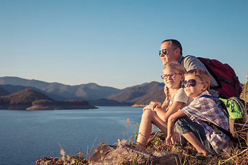 Image showing Happy family sitting near a lake at the day time.