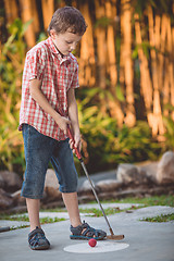 Image showing Happy little boy  playing mini golf.