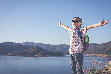 Image showing One happy little boy standing near a lake