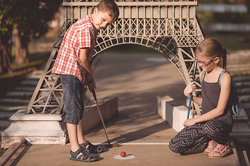 Image showing Happy brother and sister  playing mini golf.