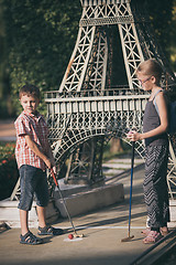 Image showing Happy brother and sister  playing mini golf.